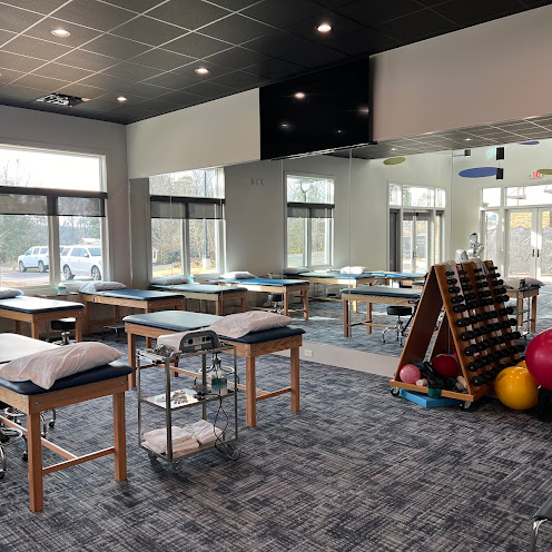 Interior of the North Oconee Physical Therapy clinic with treatment tables, mirrors, and exercise equipment